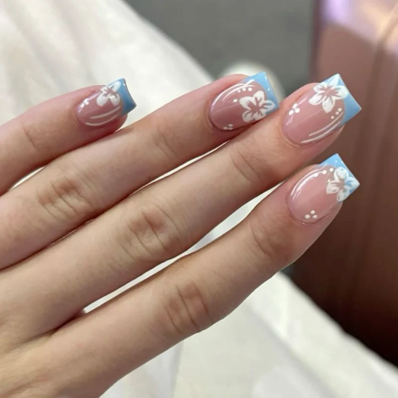 Kunstvolle Nagelkunst mit Blumen-Design und Blauem French Tip Karnz