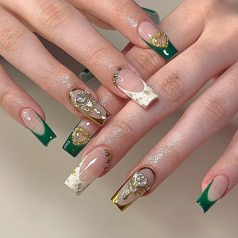 Exquisite Kunstnägel mit Goldverzierungen und Glitzerakzenten Karnz