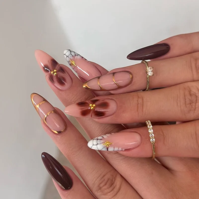 Kunstvolle Stiletto-Nägel mit Goldakzenten und dekorativen Blumenmotiven Karnz