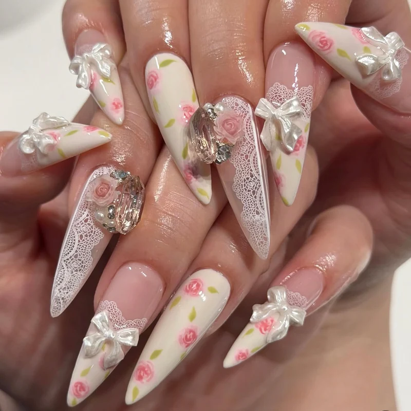 Kunstvolle Stiletto-Nägel mit floralen Akzenten und Glitzerakzenten Karnz