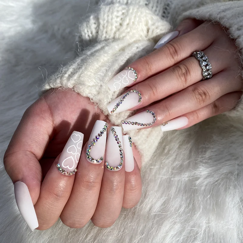 Kunstvolle Nagelverlängerungen mit Herzen-Design und Glitzerakzenten Karnz