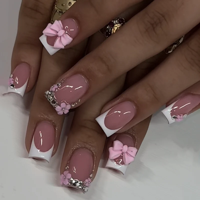 Kunstvolle Nagelverlängerungen mit glitzernden Akzenten und Schleifenverzierungen Karnz