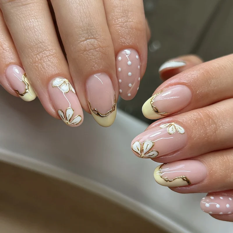 Kunstvolle Nagelverlängerungen mit floralem Design und eleganten Goldakzenten Karnz