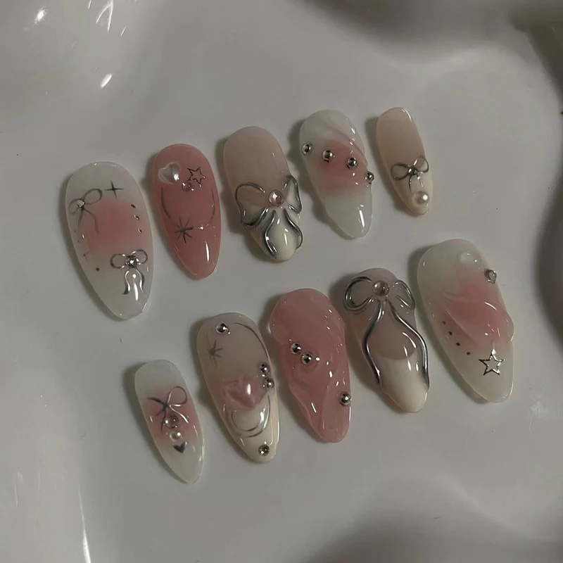 Kunstvolle Nagelspitzen mit Glitzer- und Schleifenmotiven Karnz