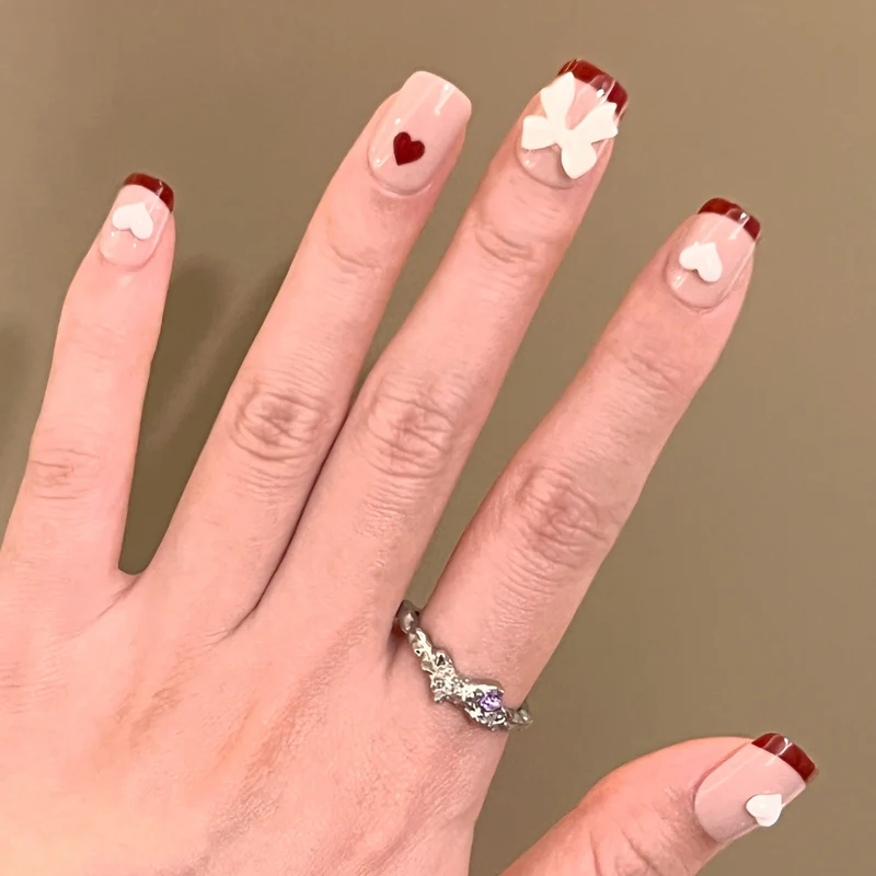 Kunstvolle Nagelkunst mit Herz- und Schleifenmotiven Karnz