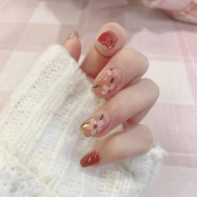 Kunstvolle Nagelkunst mit floralen Motiven und Glitzerakzenten Karnz