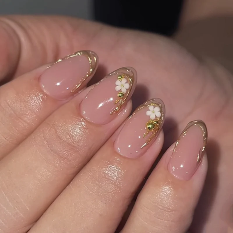 Kunstvolle Nagelgestaltung mit goldenen Akzenten und floralen Details Karnz