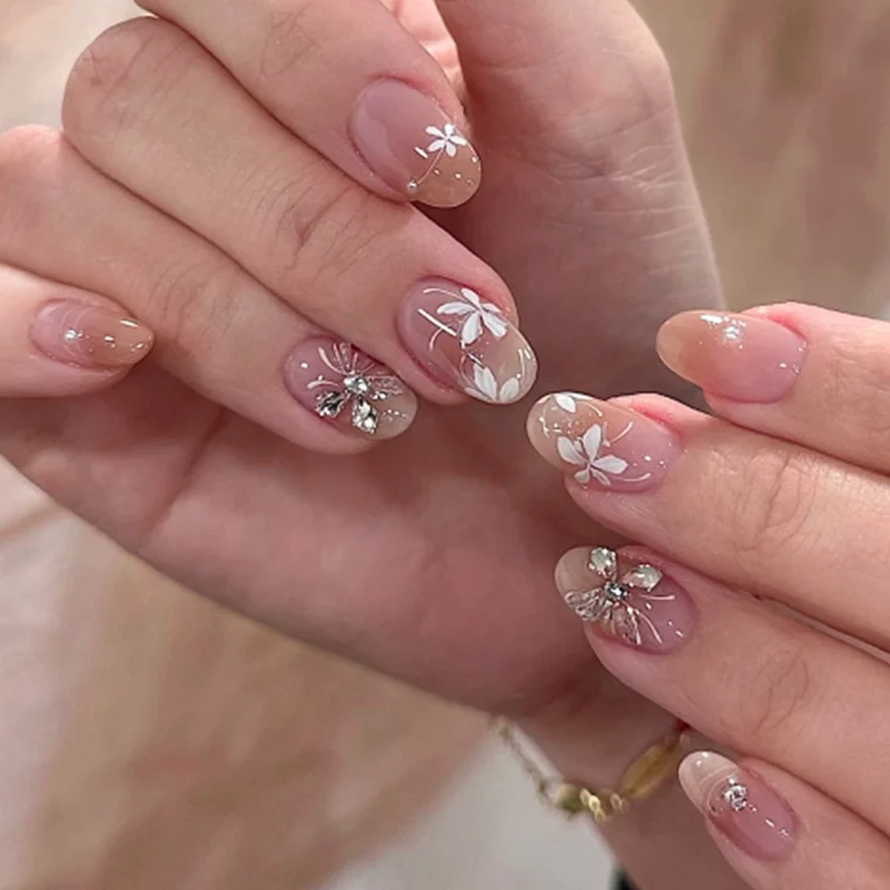 Kunstvolle Nagelgestaltung mit floralem Design und Glitzerakzenten Karnz