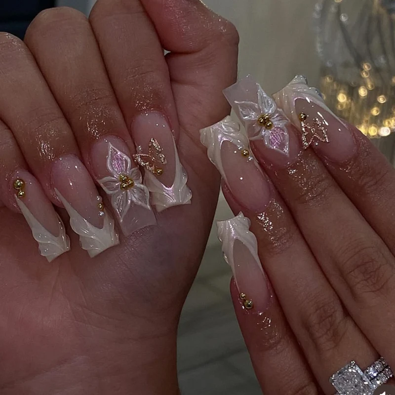 Elegante Kunstnägel mit floralem Design und Goldakzenten Karnz