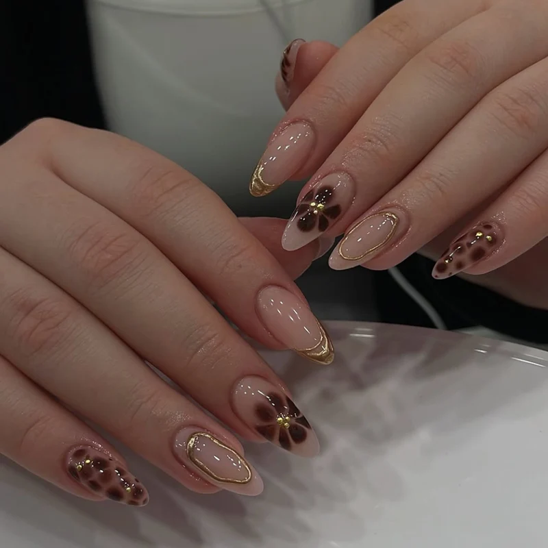 Elegante Kunstnägel mit floralem Akzent und goldenen Details Karnz