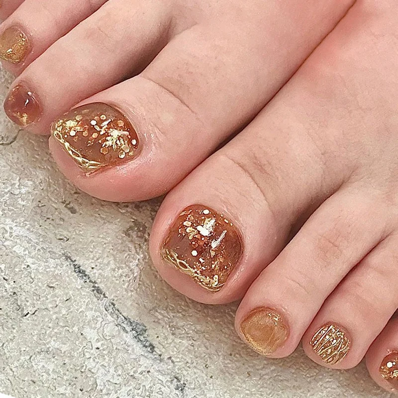 Kunstvolle Fußnagelgestaltung mit Glitzer und goldenen Akzenten Karnz