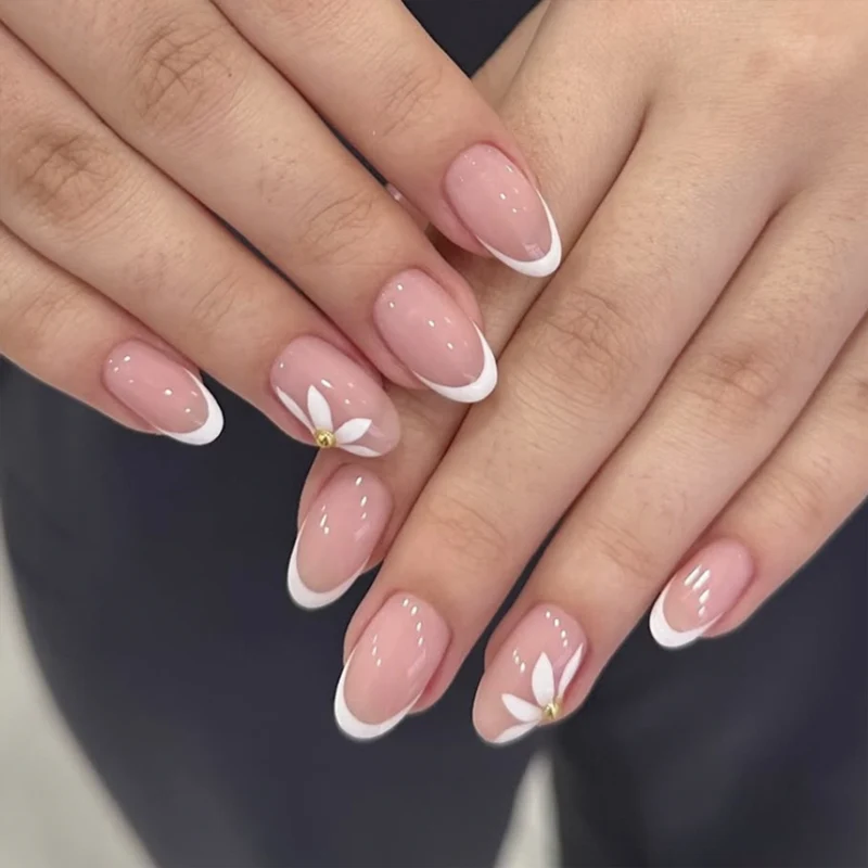 Kunstvolle French-Nägel mit zarten Blüten und Glitzerakzenten Karnz