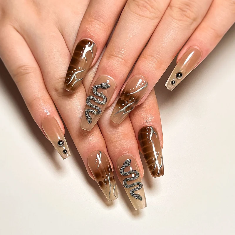 Kunstvolle Fingernägel mit Schlangen- und Glitzerakzenten Karnz